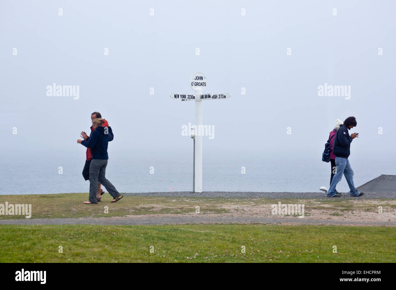 Walkers passing the sign showing distances to Land's End, John O'Groats, Caithness, Scotland Stock Photo
