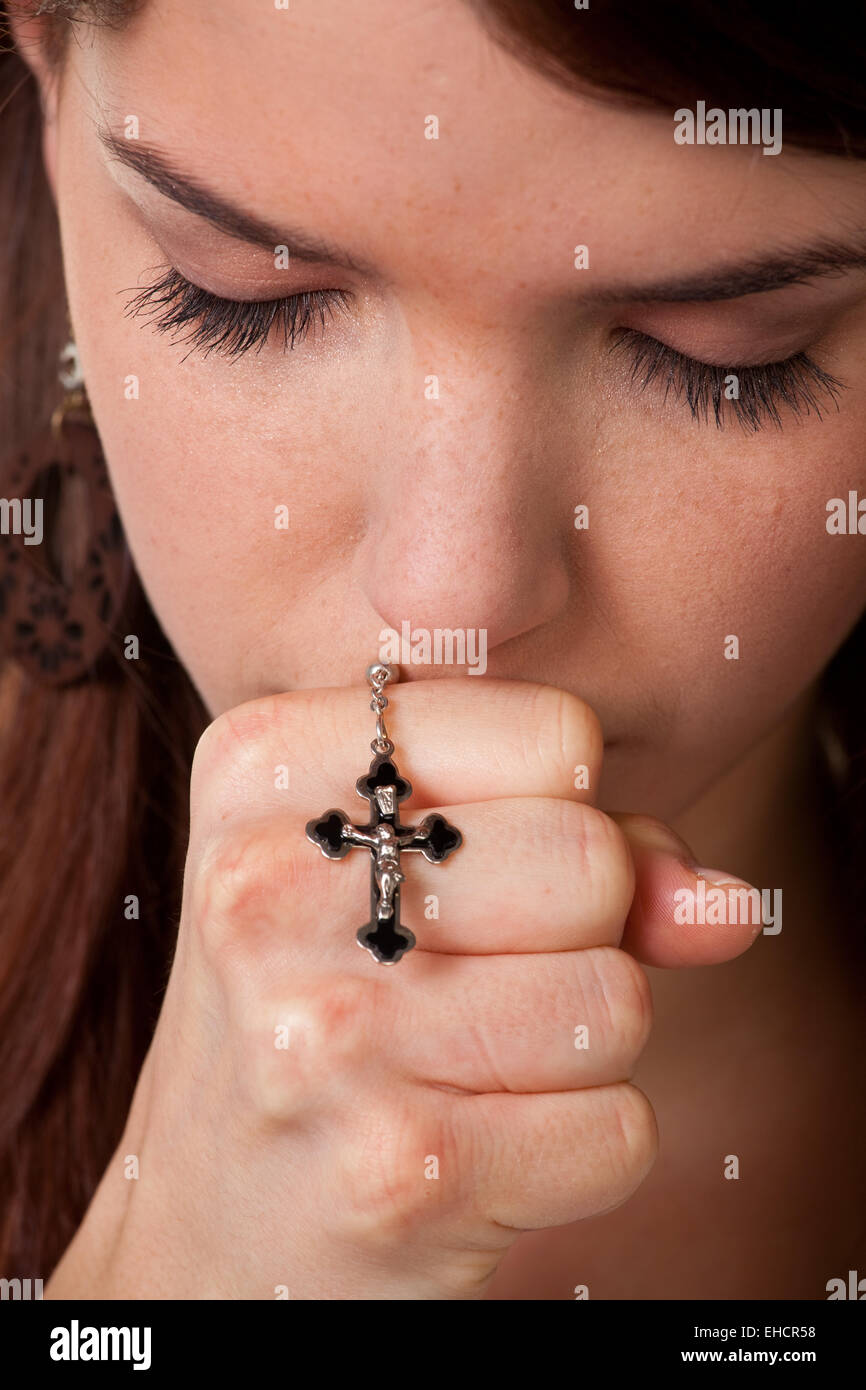 Young woman hands praying with a cross Stock Photo