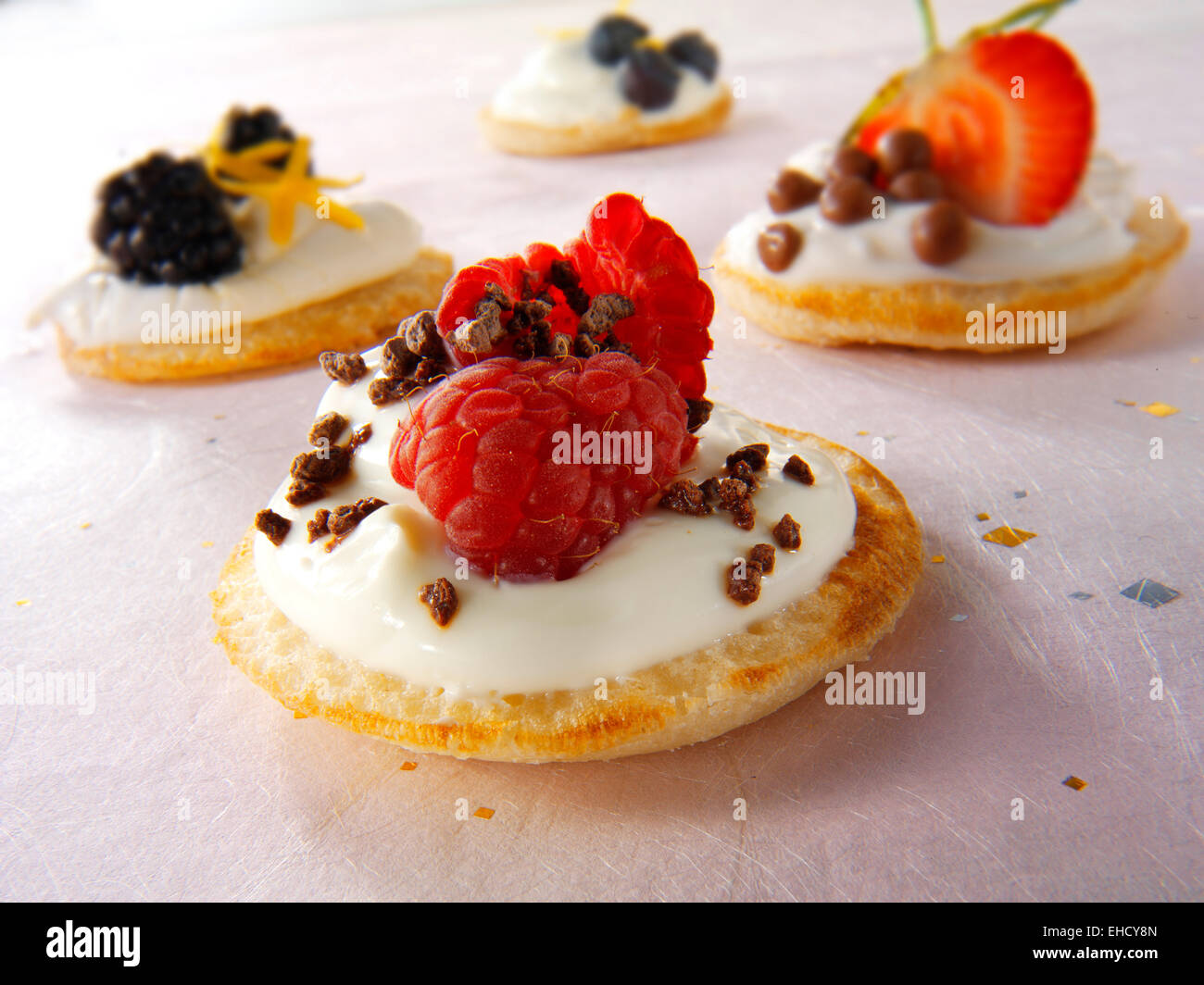 Sweet blinis canipe, blini topped with creme fraiche, raspberry and chocolate chips Stock Photo