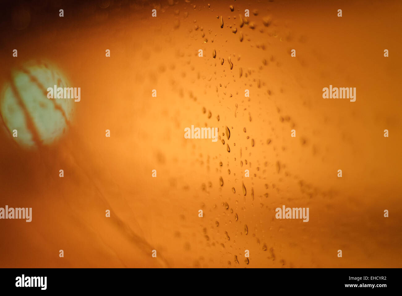 Waterdrops on a window of car with orange background Stock Photo