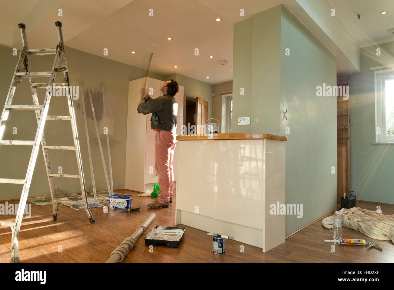 Man Using A Paint Roller On The Ceiling Decorating The