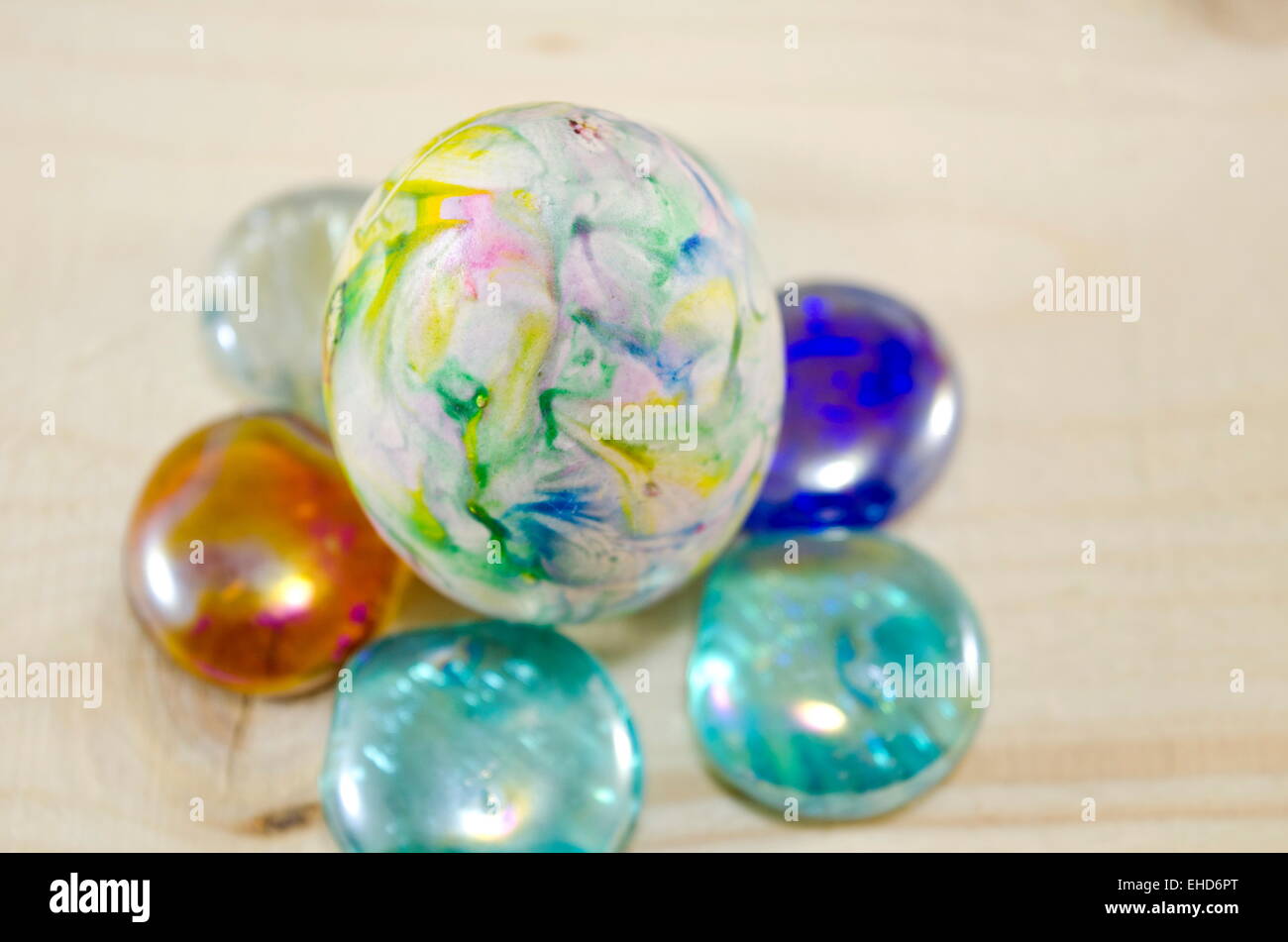 Hand painted egg on colorful pearls on a wooden table Stock Photo
