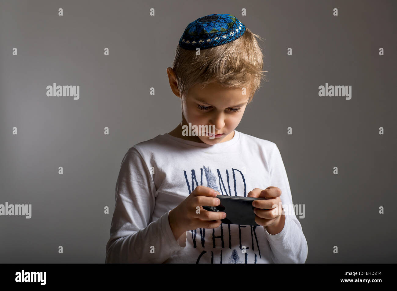 studio portrait of white boy with Jews kipa or yarmulke with mobile ...