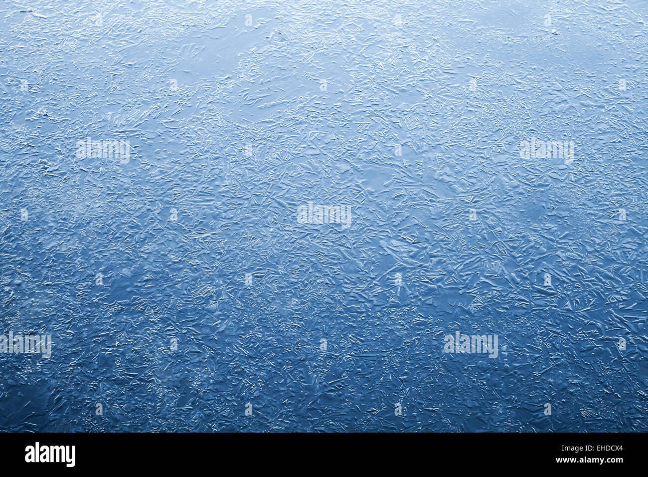 Thin ice layer of frozen river water. Dark blue natural background