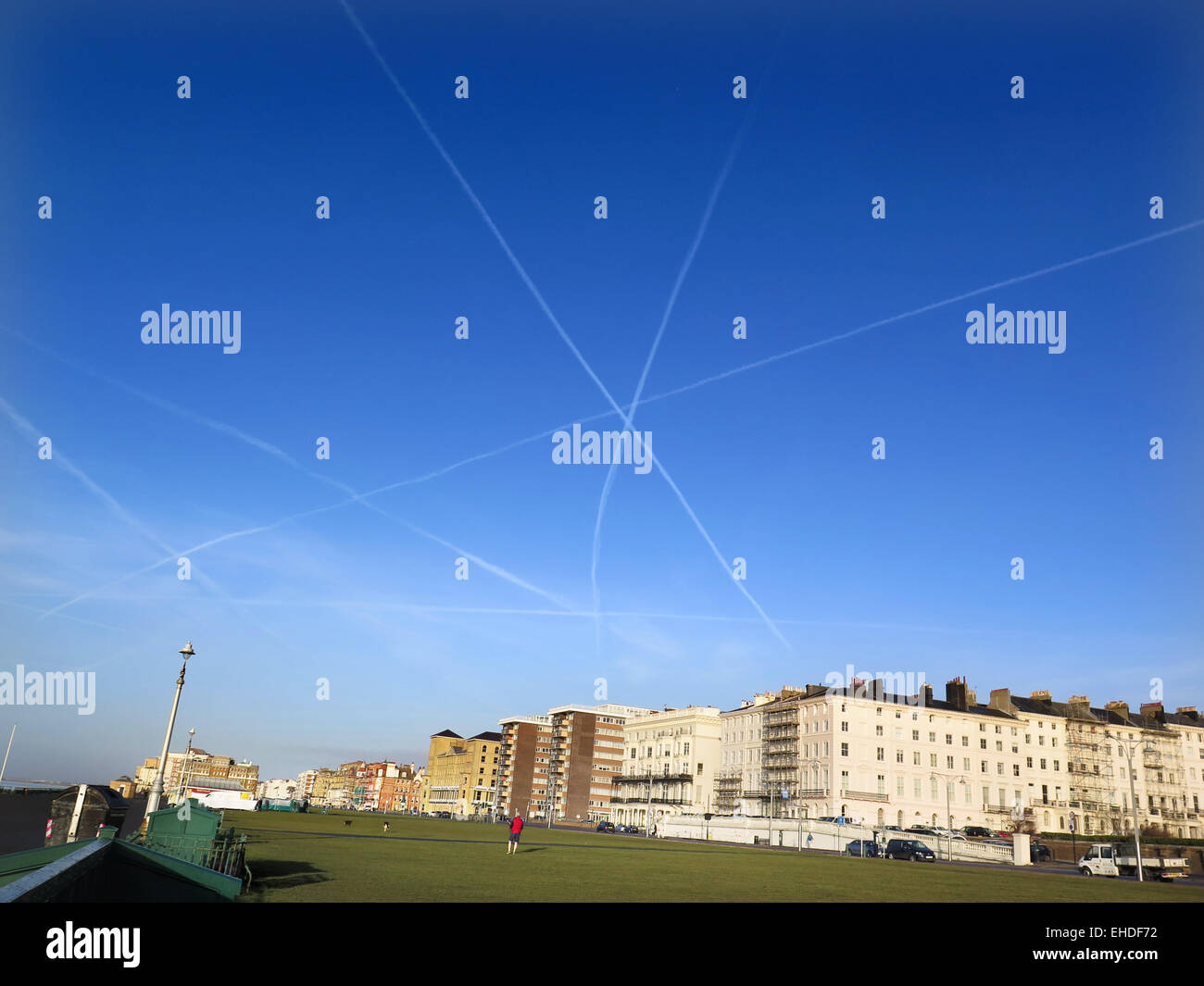The vapour trails of three planes form a star shaped with their Contrails over Hove lawns on Brighton and Hove seafront. The planes were departing from Gatwick airport for Europe. Stock Photo