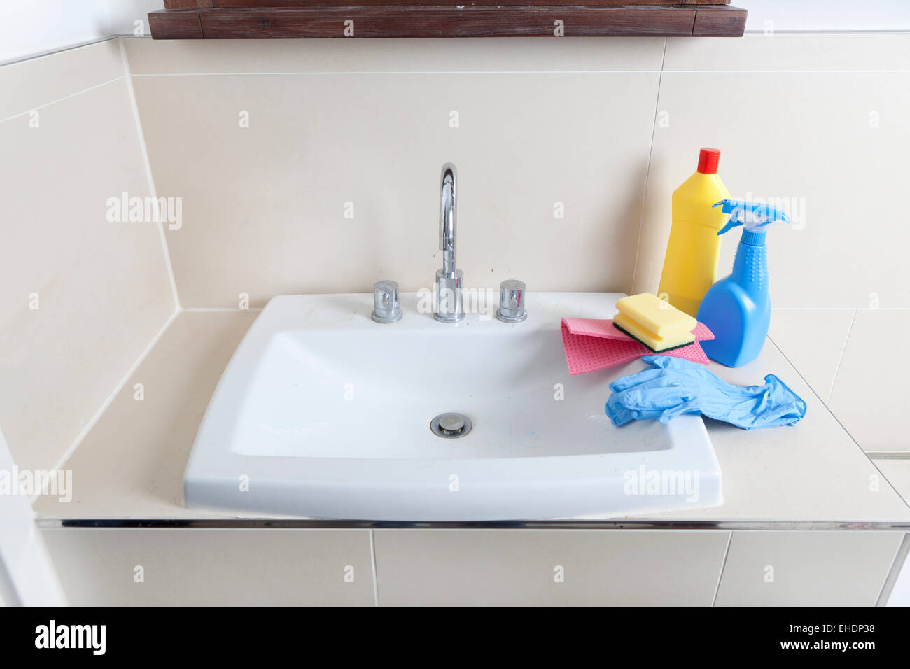 a dirty and calcified sink with cleaning gloves and cleaning products