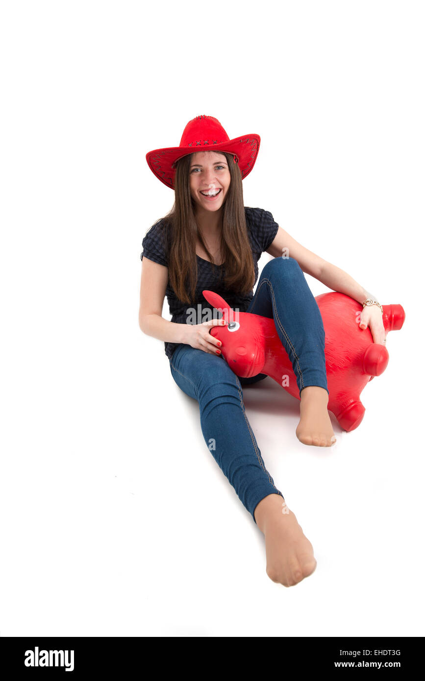 Young girl with red cowboy hat riding o toy horse isolated Stock Photo