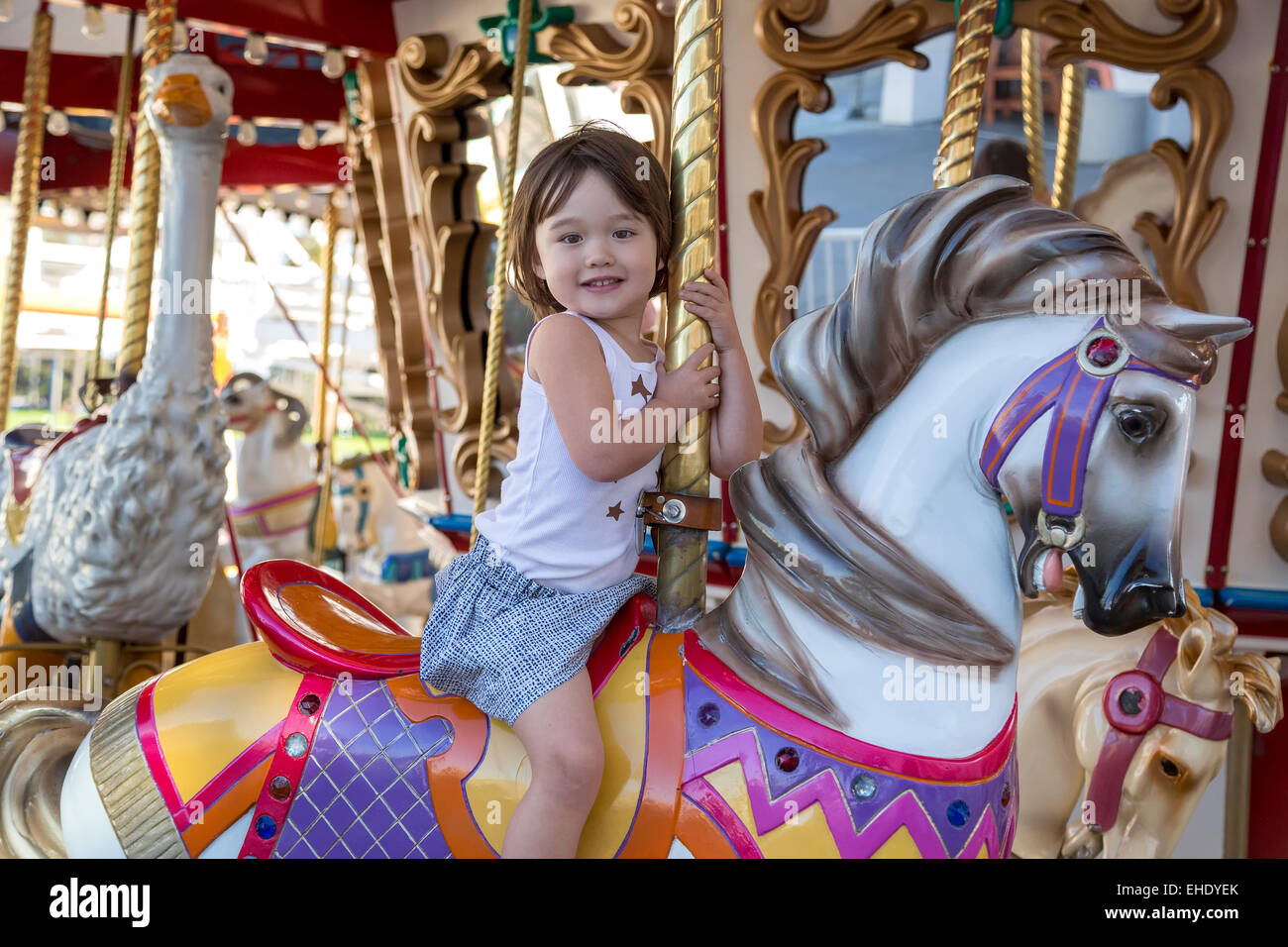 Happy girl riding the merry go round Stock Photo