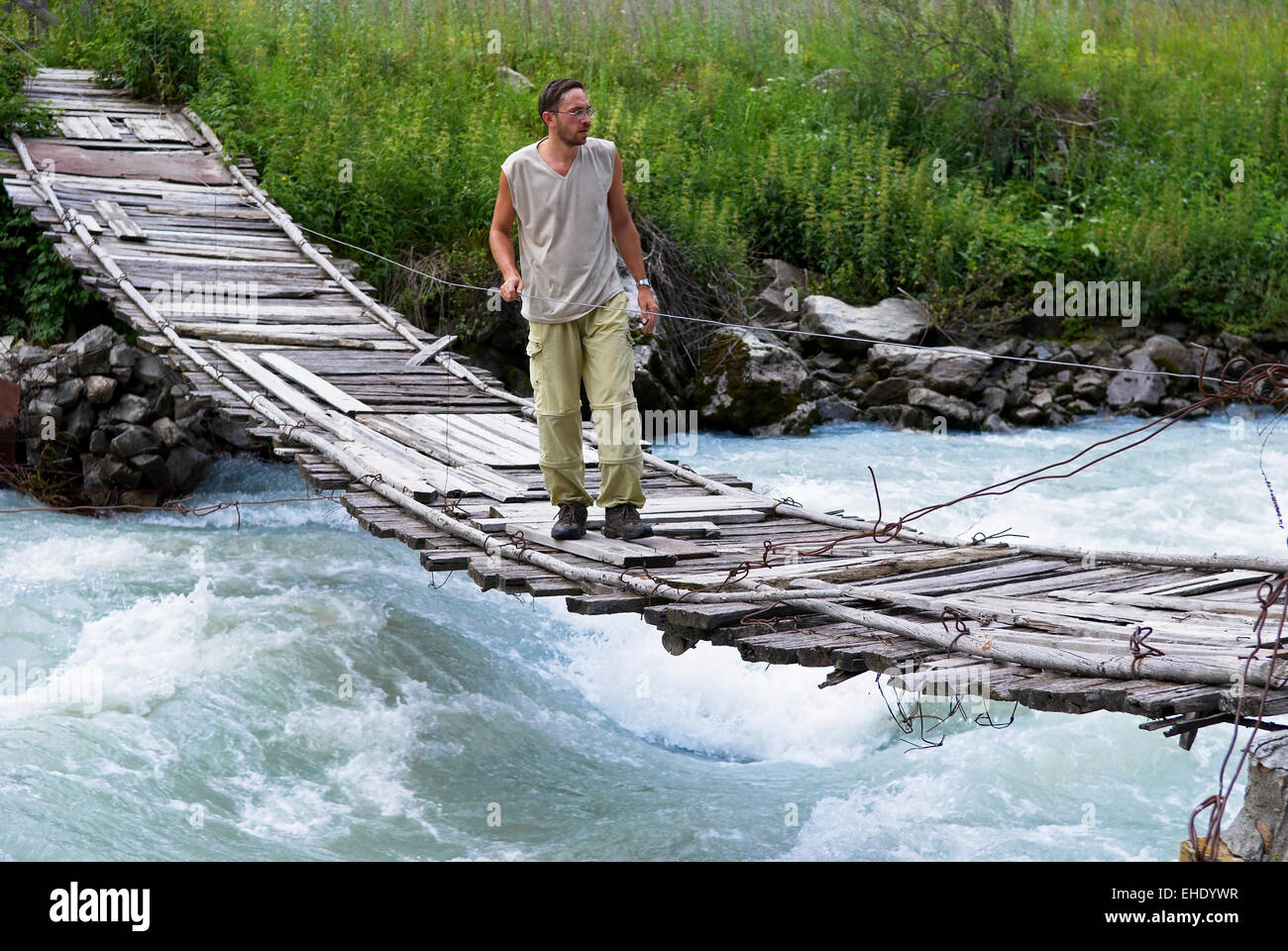 Man on old suspension bridge Stock Photo
