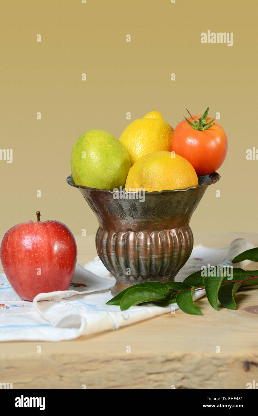 Vase with produce on wooden table over light yellow background Stock Photo