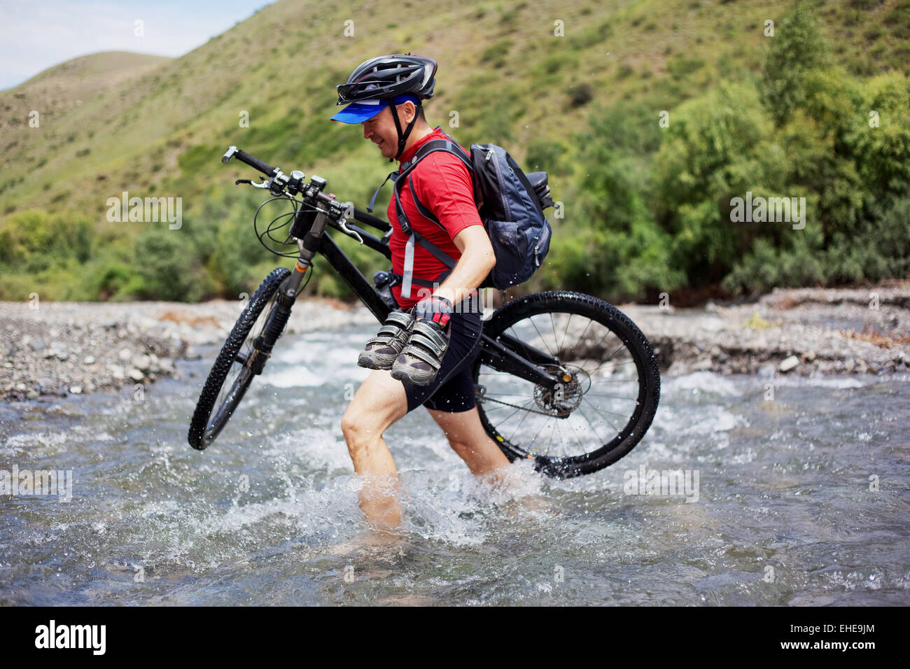 Biker goes over the mountain river ford Stock Photo