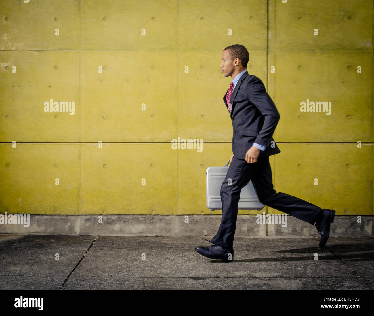Businessman portrait wearing suit and tie running with Halliburton Zero Aluminum Aluminium briefcase / attache case Stock Photo