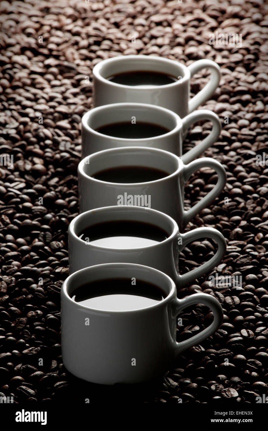 White coffee cups in row on coffee beans Stock Photo Alamy