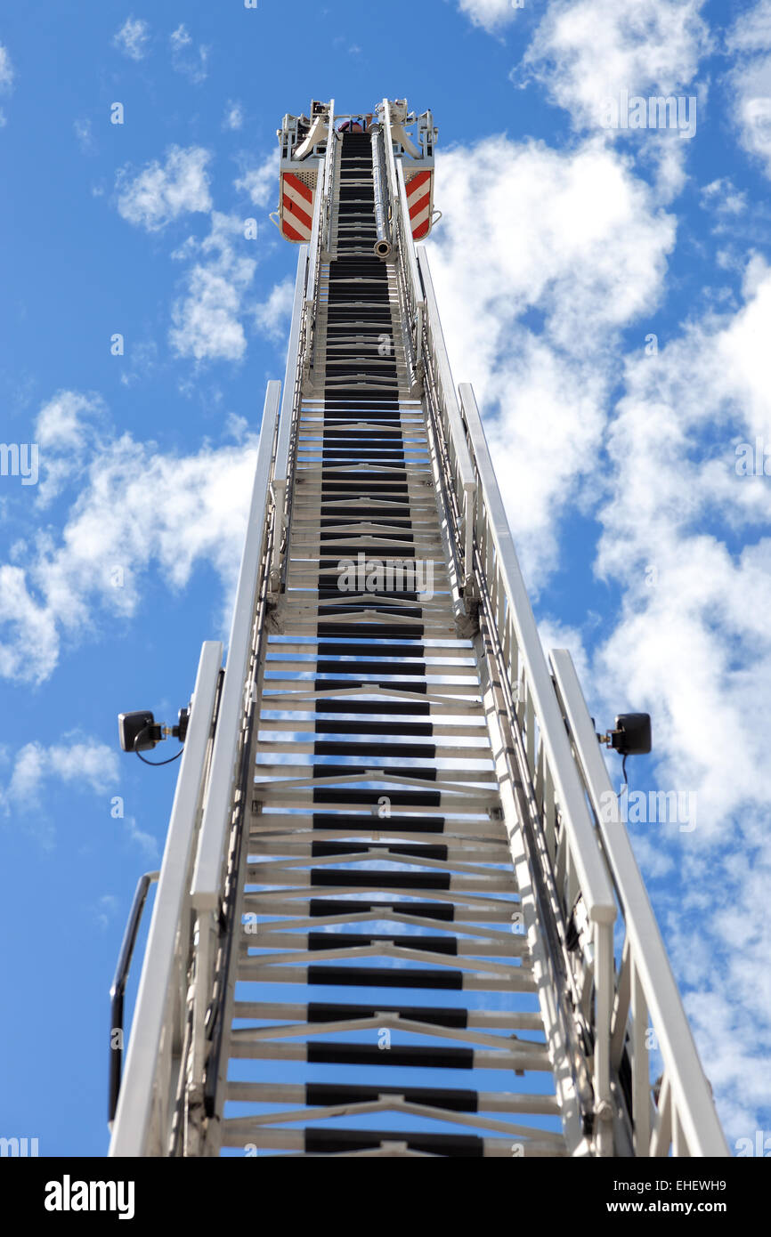 Fire truck ladder leading up into blue sky. Stock Photo