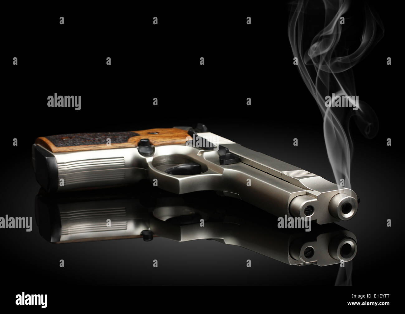 Chromed handgun on black background with smoke Stock Photo