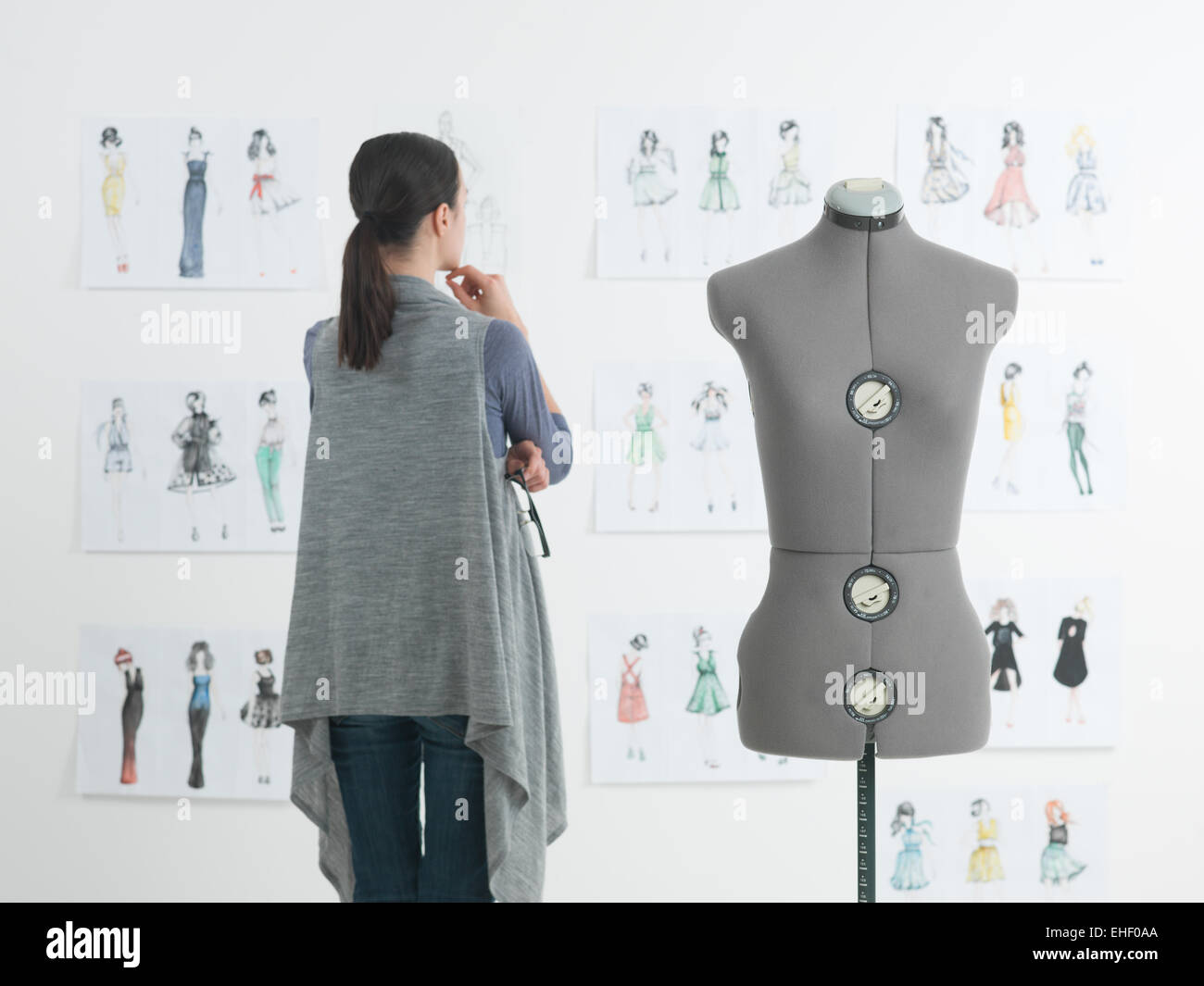successful female fashion designer looking at drawings in her studio ...