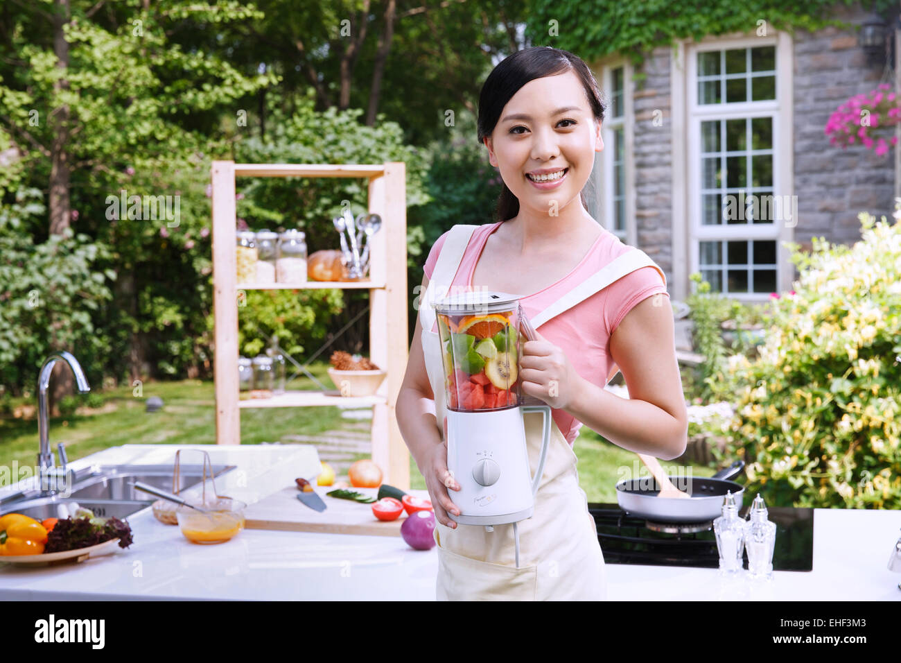 Oriental woman holding a blender outdoors in the kitchen Stock Photo