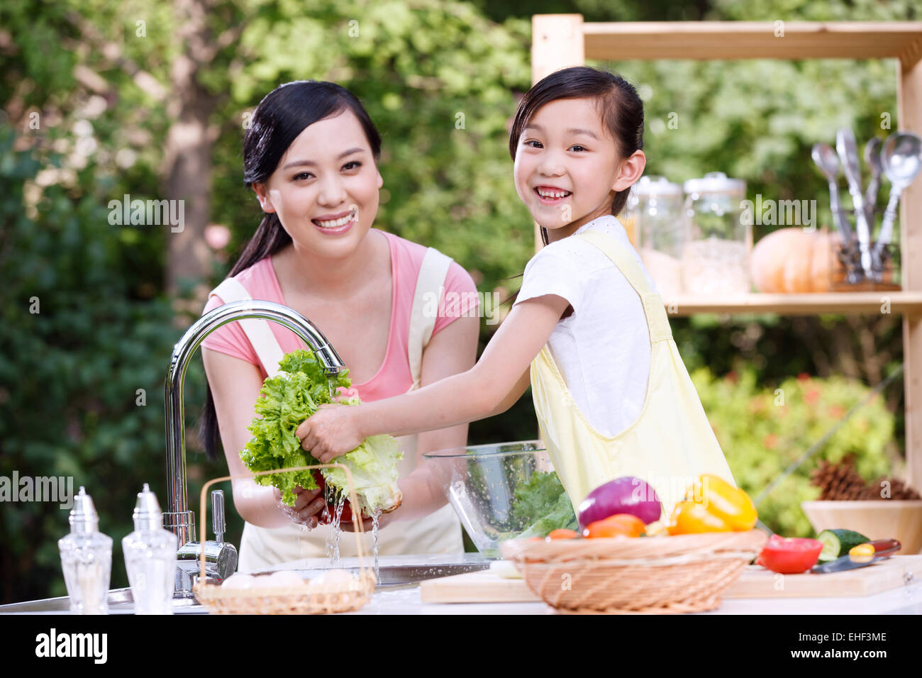 Mother and daughter in the outdoor kitchen cleaning vegetables Stock Photo