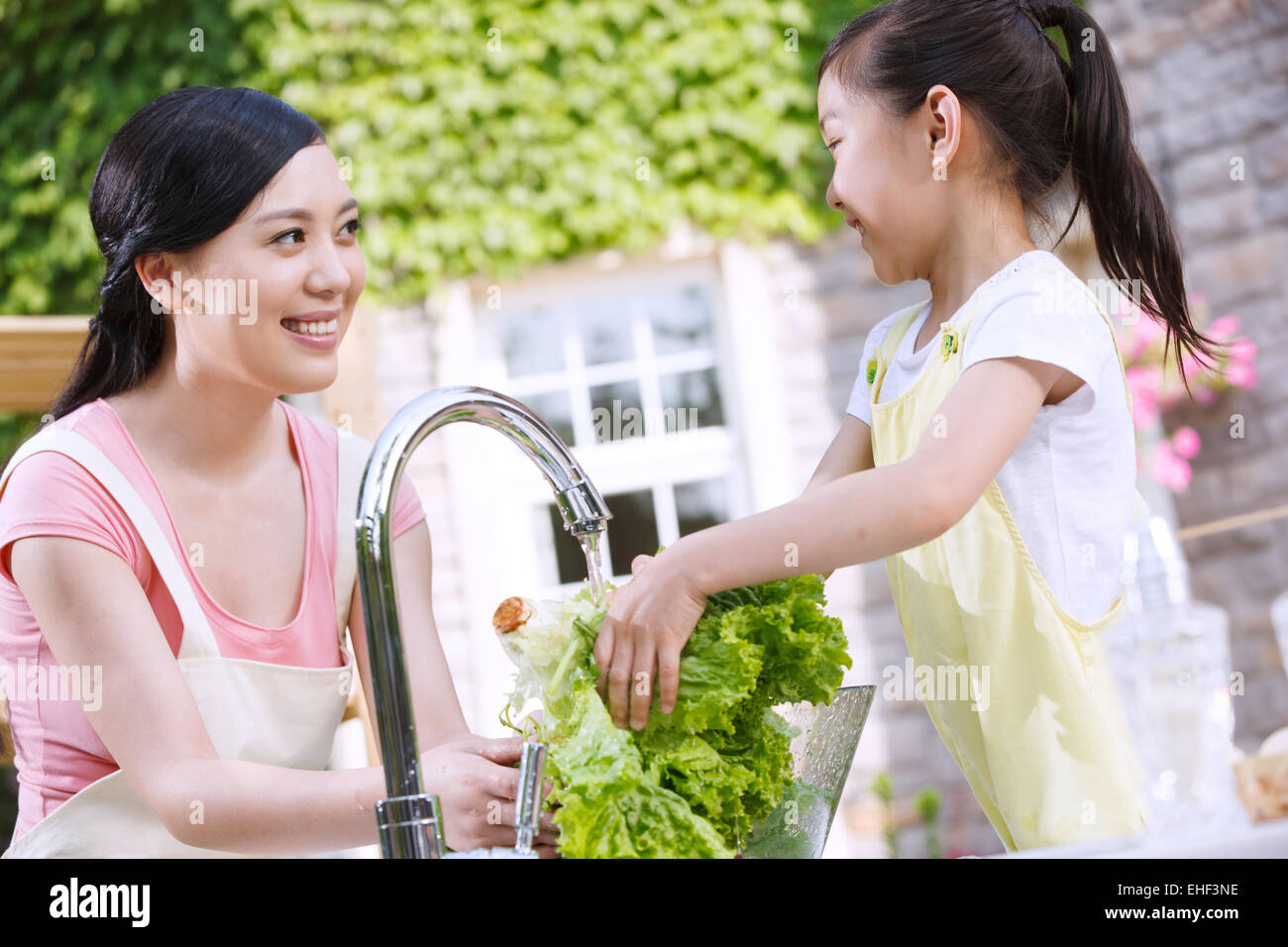 Mother and daughter prepare ingredients in outdoor kitchen Stock Photo