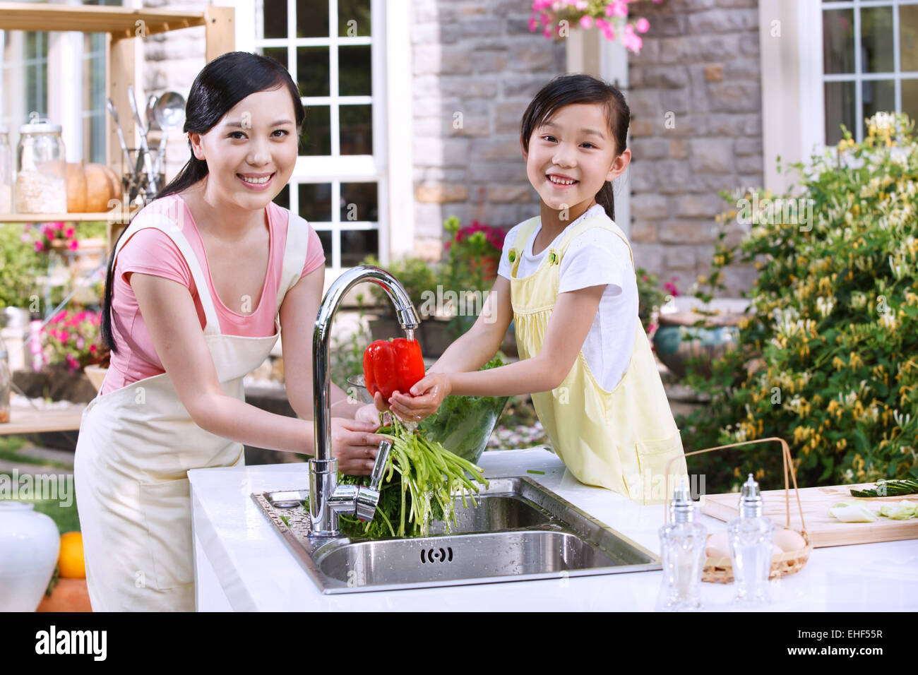 Mother and daughter in the outdoor kitchen cleaning vegetables Stock Photo