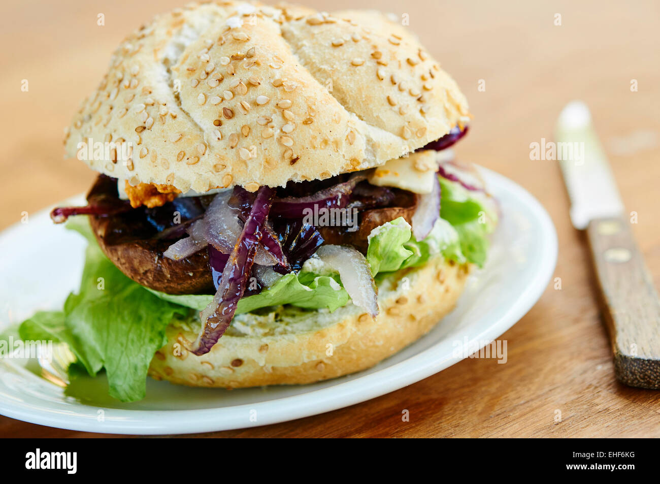 Portabello mushroom burger with fried onions, vegan cheese and lettuce. Stock Photo