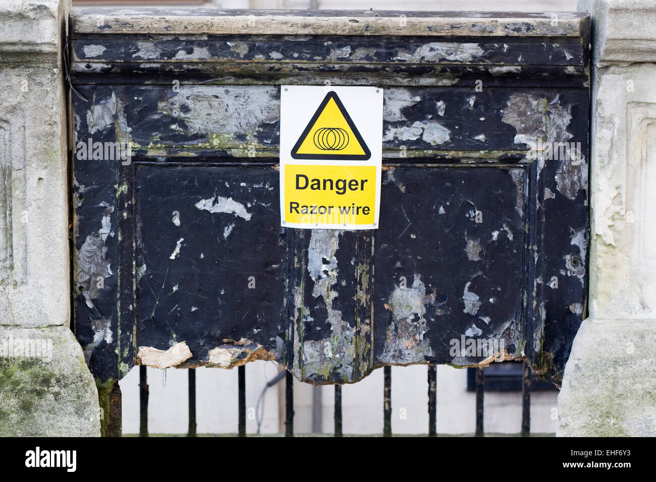 Broken wooden door with a warning of razor wire hi-res stock ...