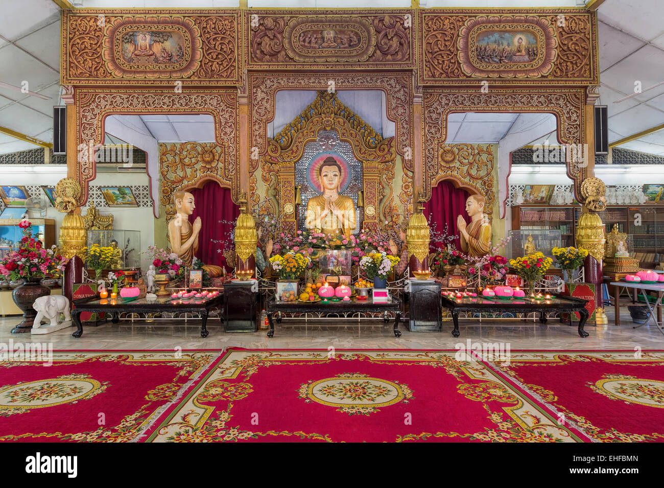 Dhammikarama Burmese Buddhist temple Cambodia Myanmar Buddha statue gold gilt monk pagoda hallway marble flooring reflection Stock Photo