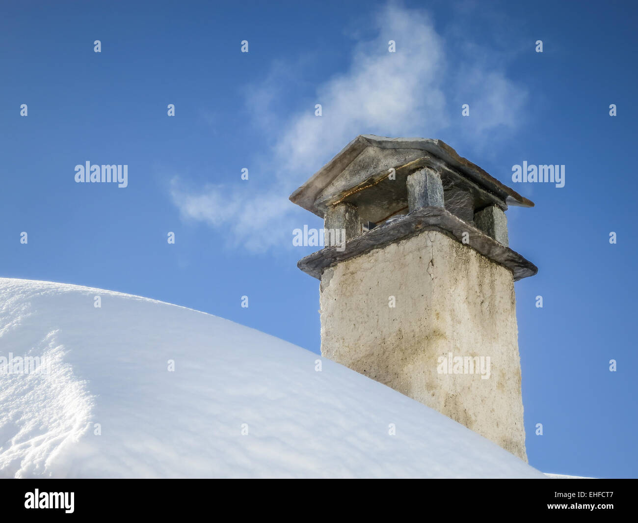 Smoke spreading from old mountain chimney on snowy roof. Vintage, old house on the mountain in winter. Warm and cold. Stock Photo