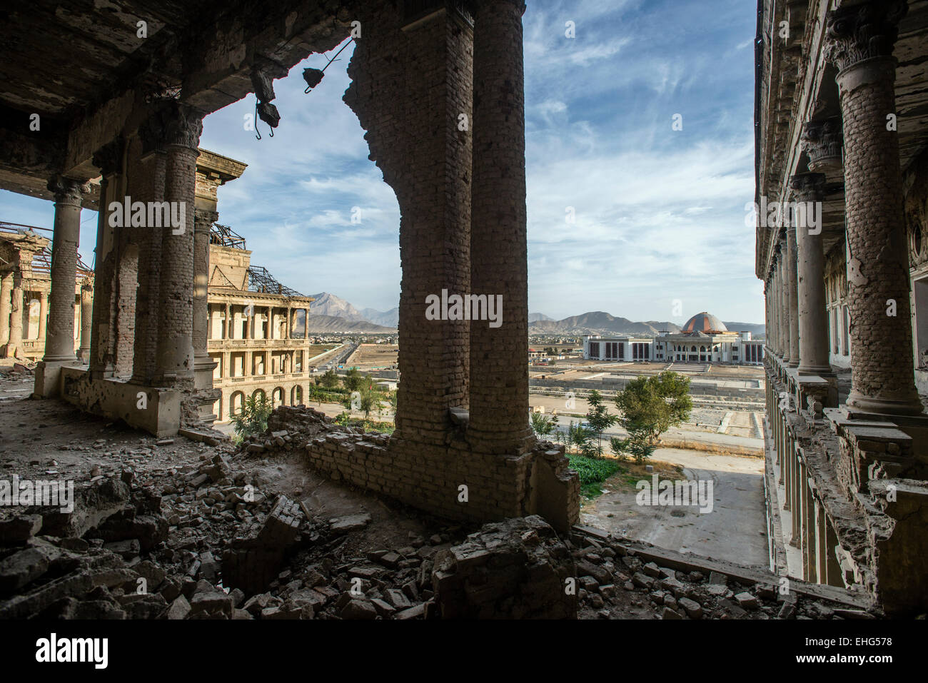 Ruined corridor of Darul Aman Palace during Mujahideen factions fought for control of Kabul in the early 1990s and building of new parliament on background, Kabul, Afghanistan Stock Photo