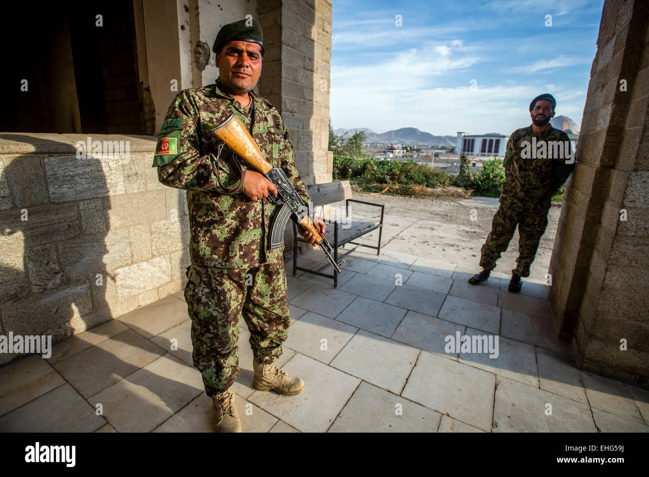 Guard of Darul Aman Palace, ruined during Mujahideen factions fought for control of Kabul in the early 1990s, and building of new parliament on background, Kabul, Afghanistan Stock Photo