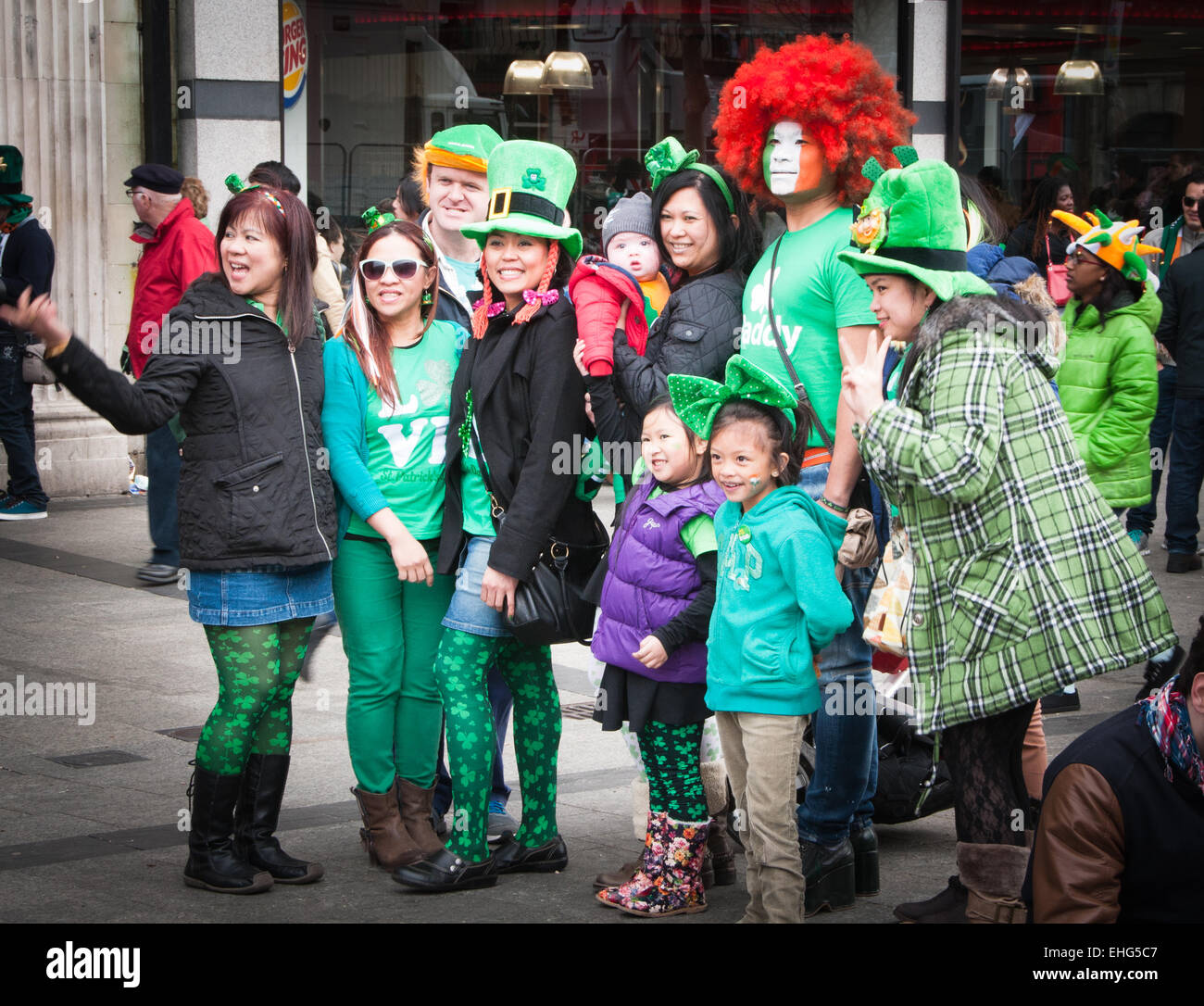 Family of Asian tourists enjoy St Patrick's day festival in Dublin Ireland wearing green clothes, facepaint and leprechaun hats. Stock Photo