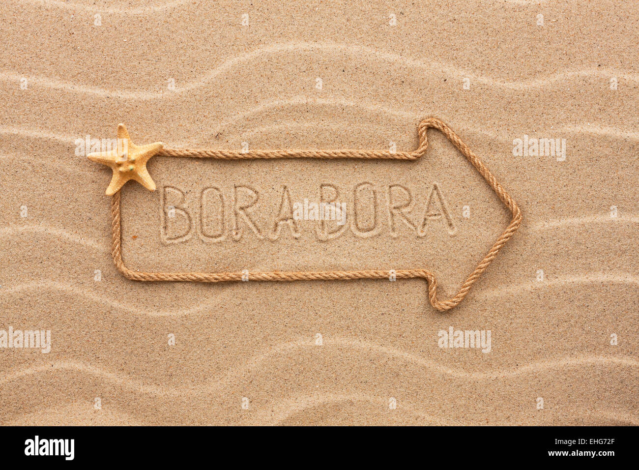 Arrow made of rope and sea shells with the word Bora Bora on the sand, as background Stock Photo