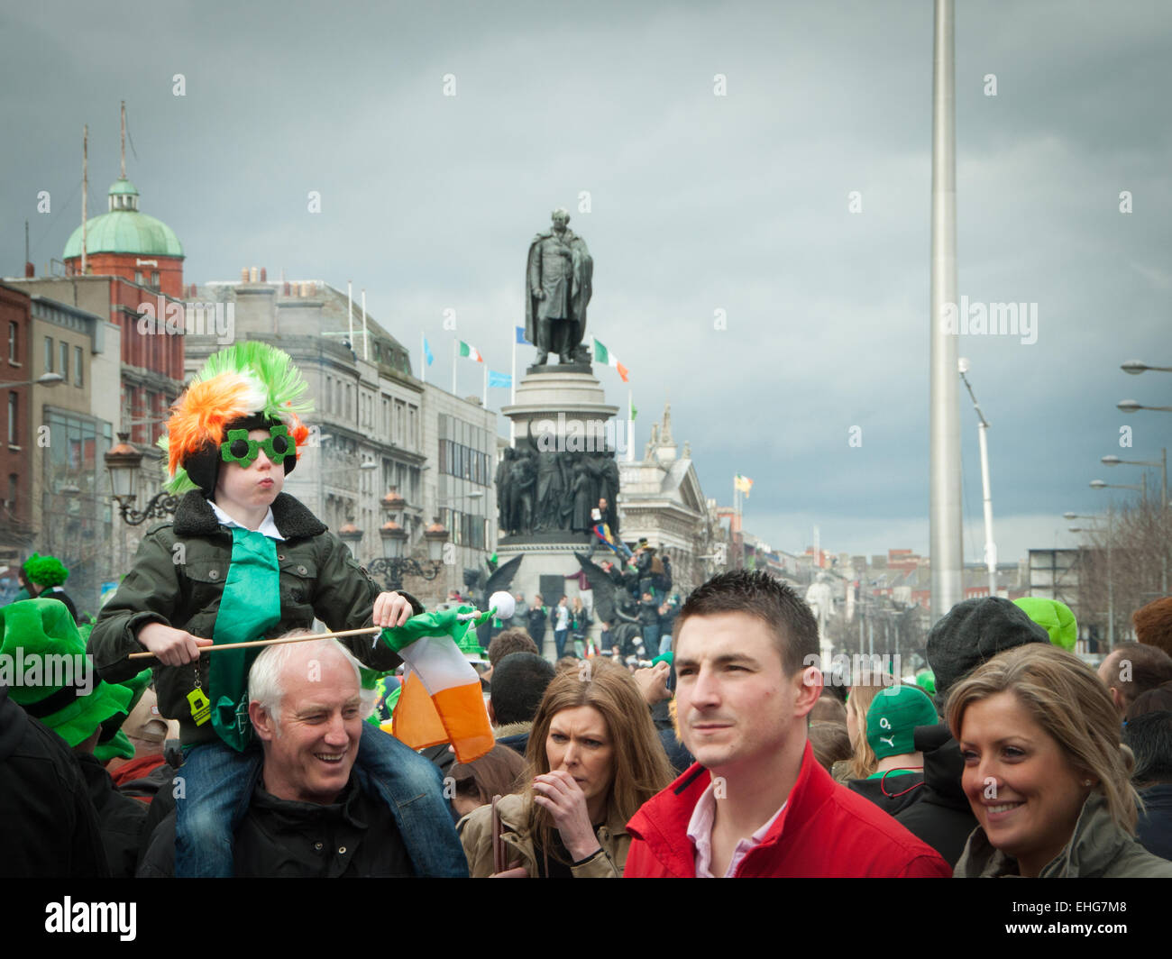 Young boy on father's shoulders has Irish wig, glasses and Irish flag on St Patrick's day in O'Connell Street Dublin Ireland Stock Photo