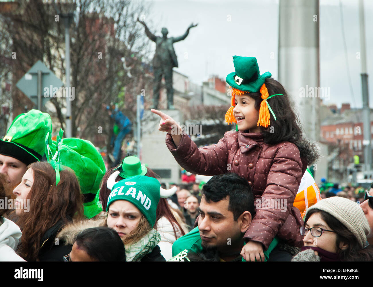Young girl enjoys the St Patrick's day parade on O'Connell street Dublin wearing green hat and sitting on her father's shoulders Stock Photo