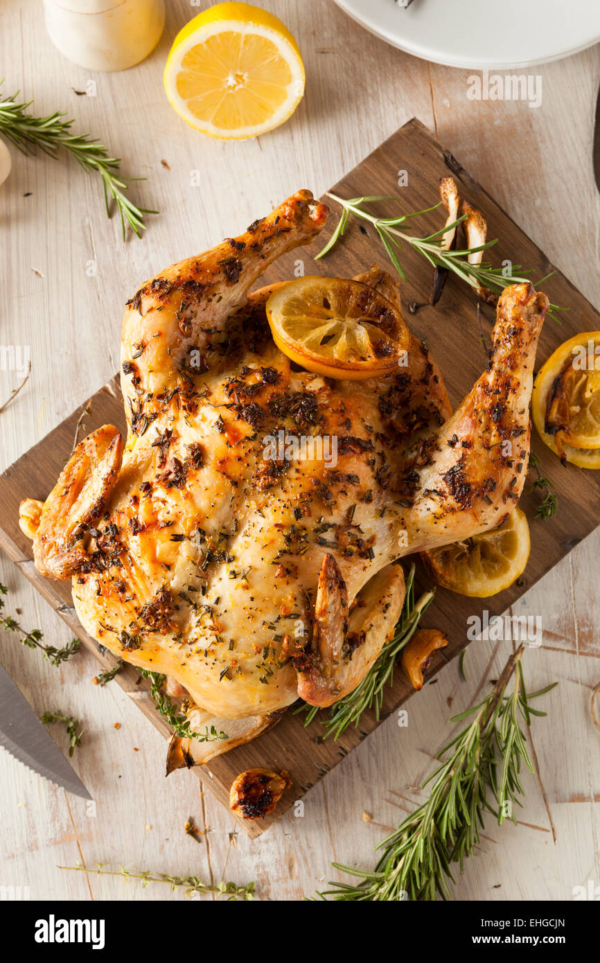 Homemade Lemon and Herb Whole Chicken on a Cutting Board Stock Photo