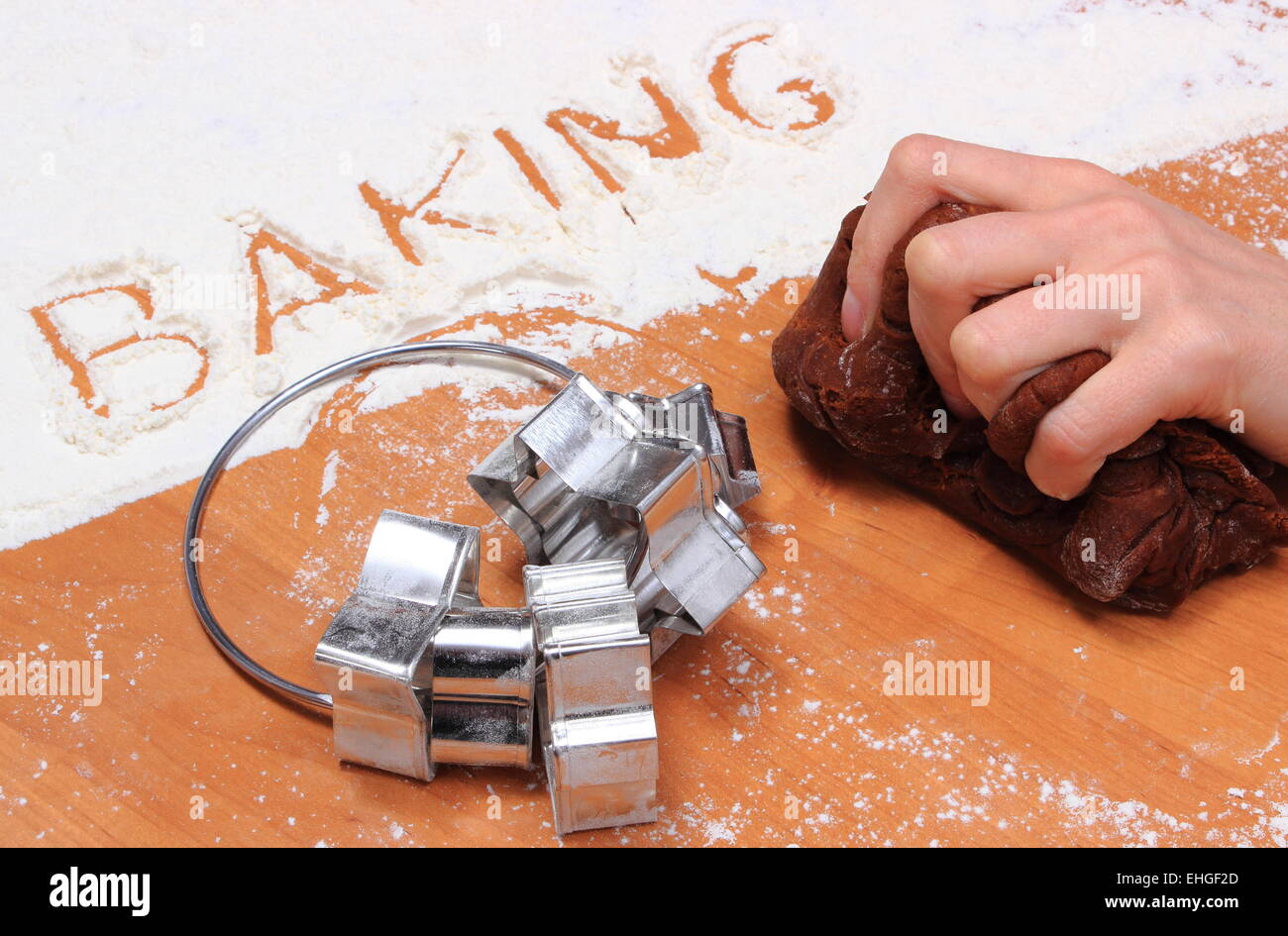 Hand of woman kneading dough for cookies, word baking in white flour and accessories for baking, concept for baking Stock Photo