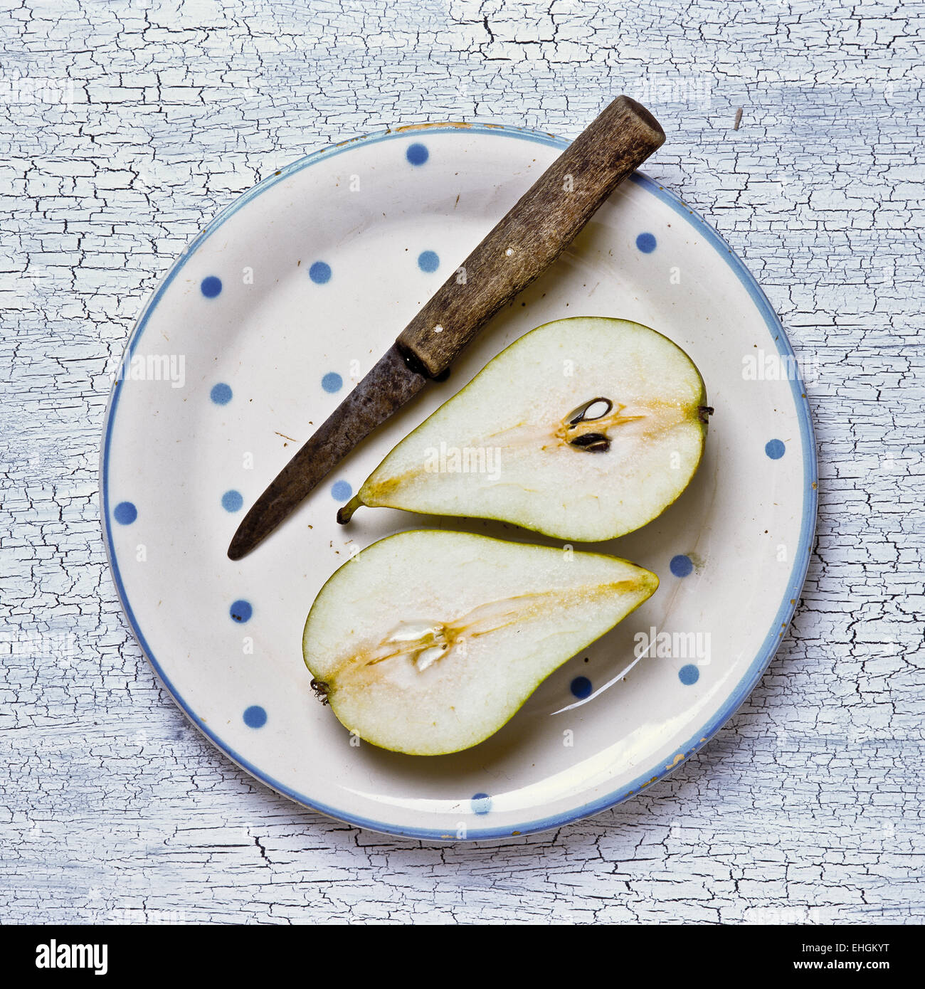 Halved pear and knife on spotted with plate Stock Photo