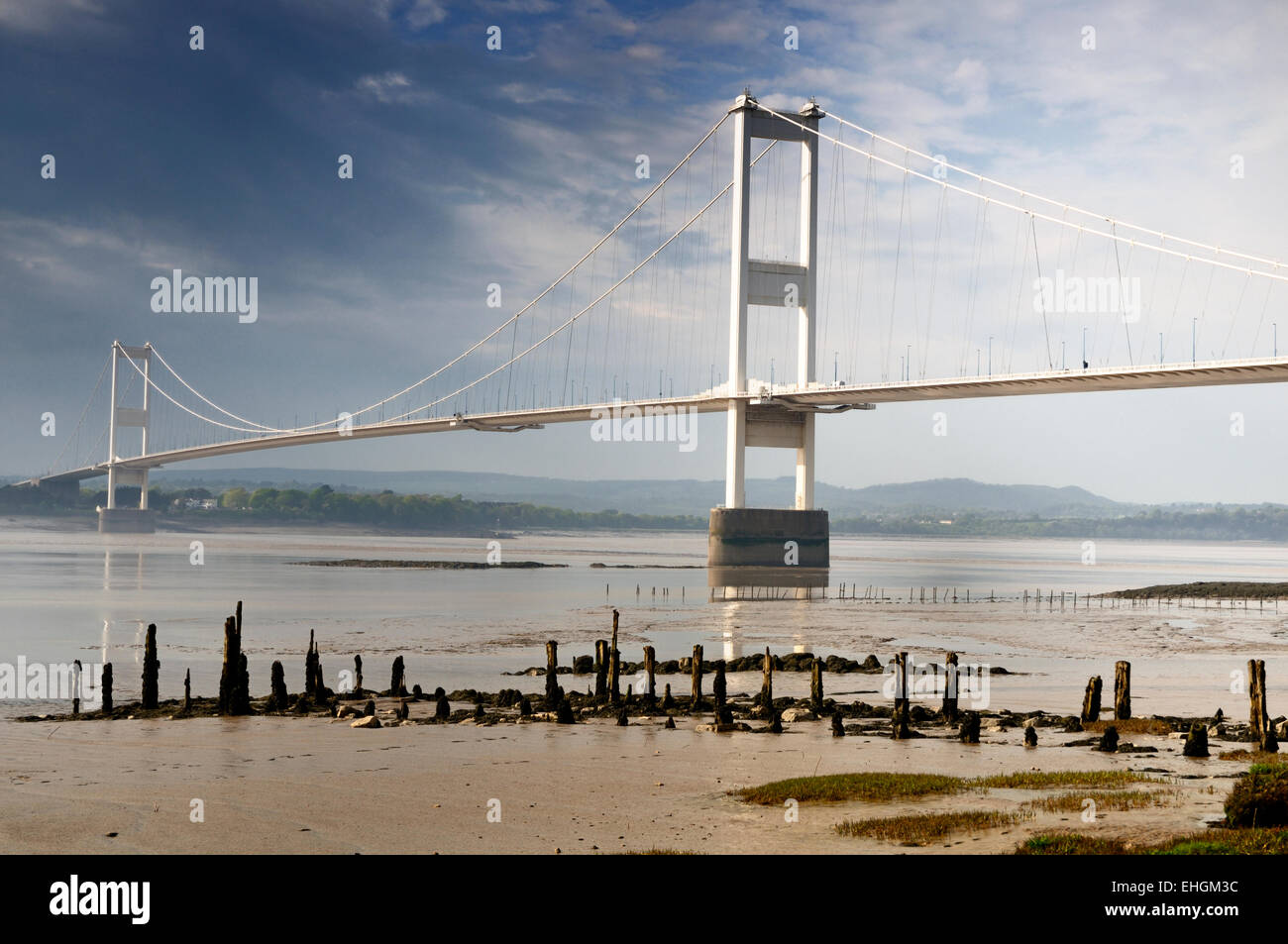 The first Severn suspension bridge spanning the Severn estuary juxtaposed with the remains of a jetty  and older crossing. Stock Photo