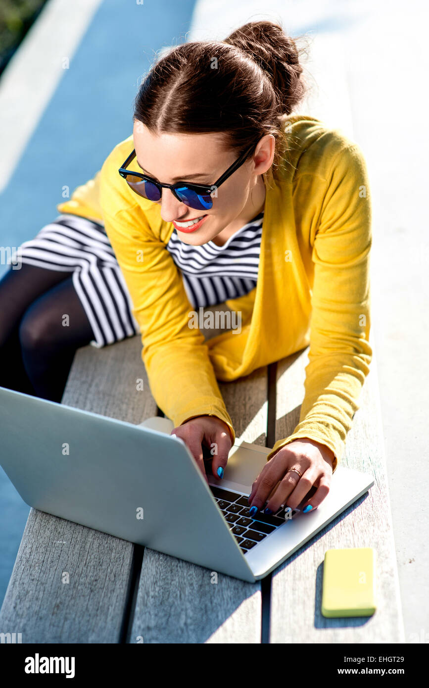 Woman with laptop and phone outdoors Stock Photo