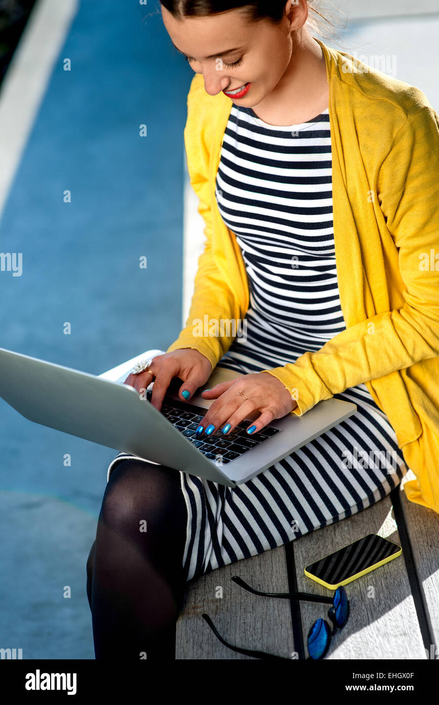 Woman with laptop and phone outdoors Stock Photo