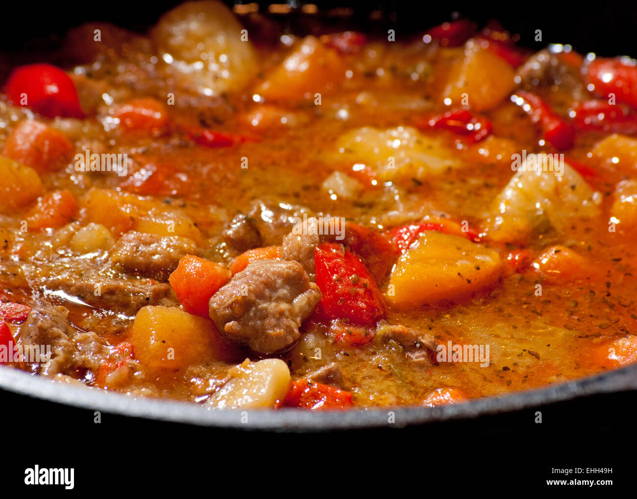 Meat and vegetable stew cooking in a black cast iron pot Stock Photo