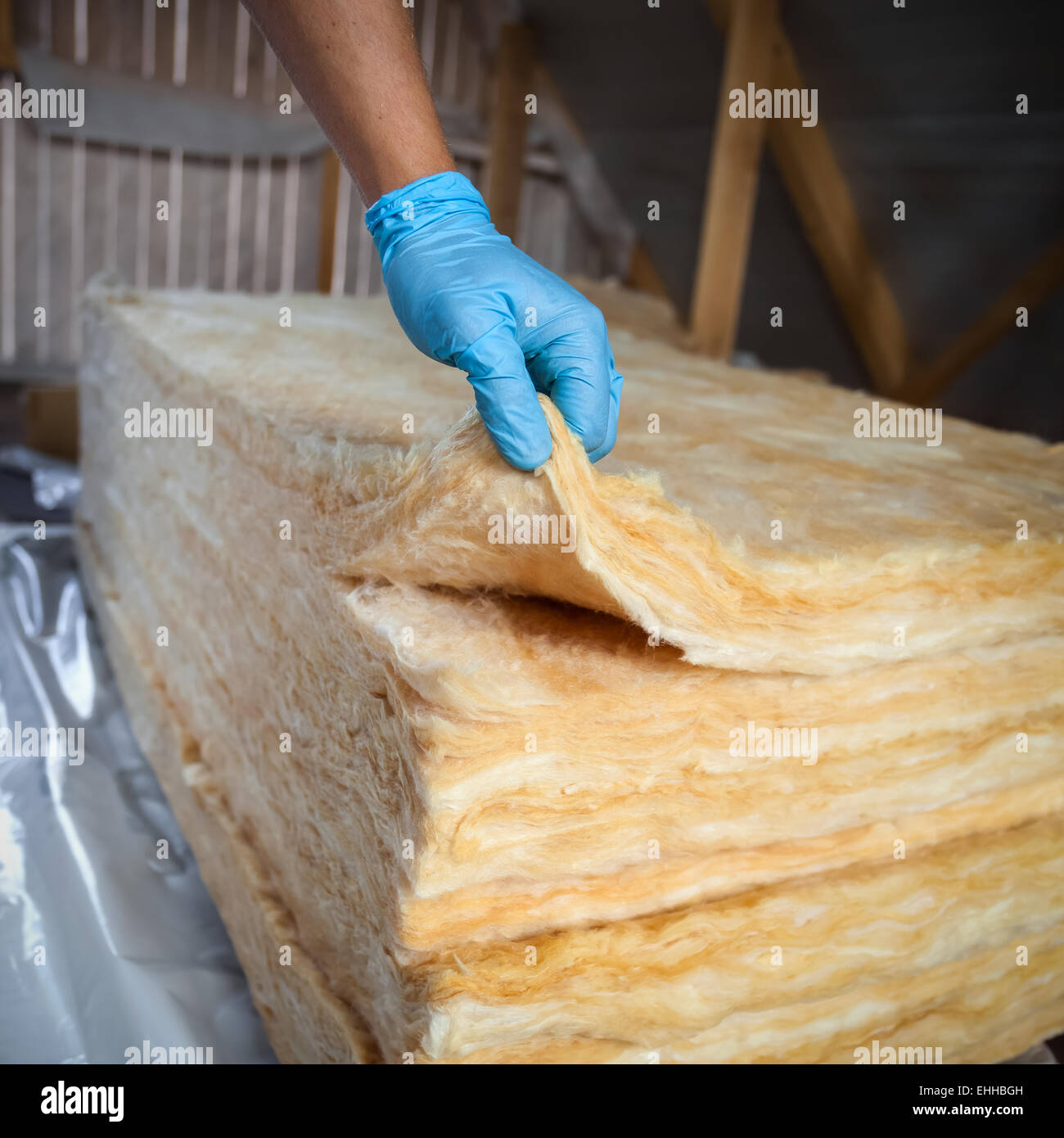 Hand in gloves holding mineral wool,  building under construction Stock Photo