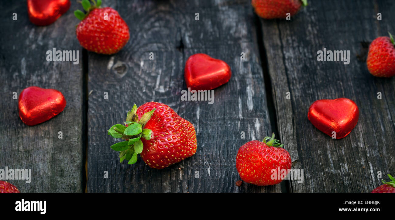 Fresh red strawberries and chocolate heart candy on old wooden table ...