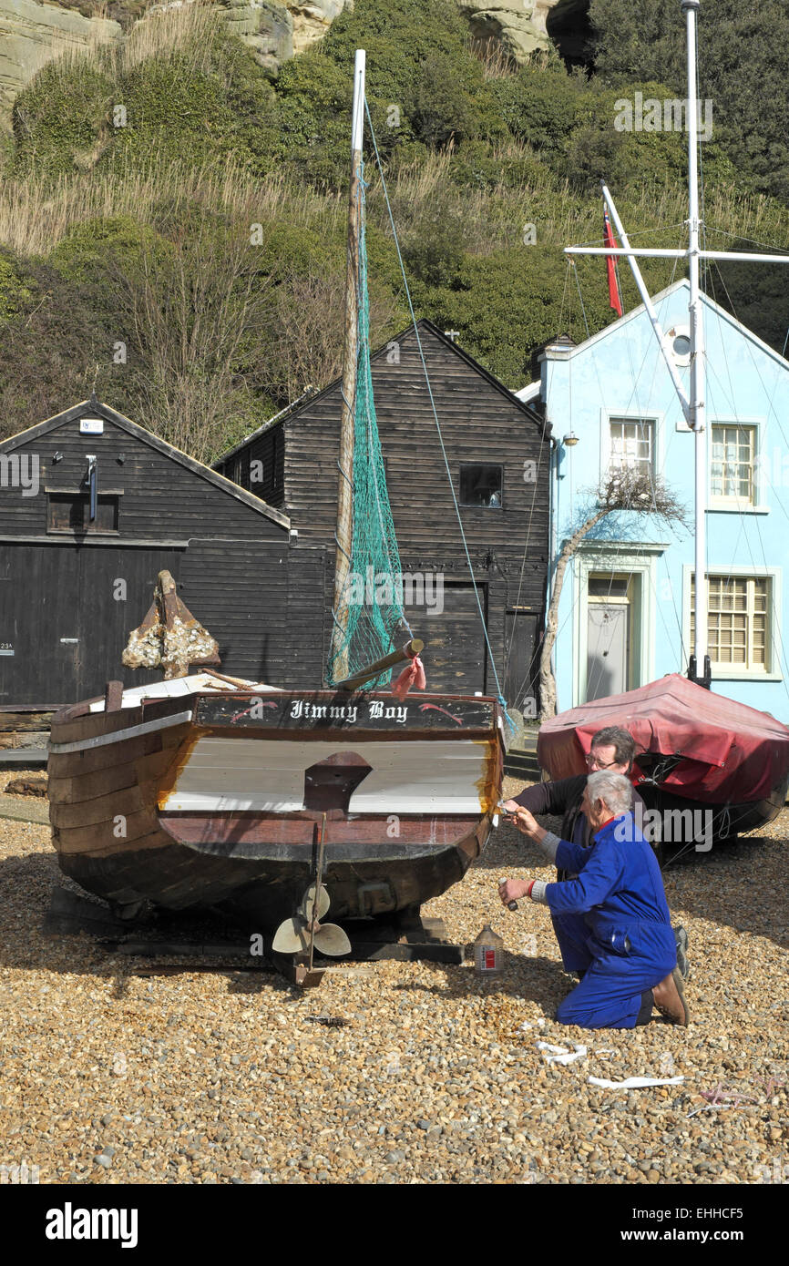 Hastings men painting historic boat on the stade, Hastings Maritime Heritage Quarter, East Sussex, England, UK Stock Photo