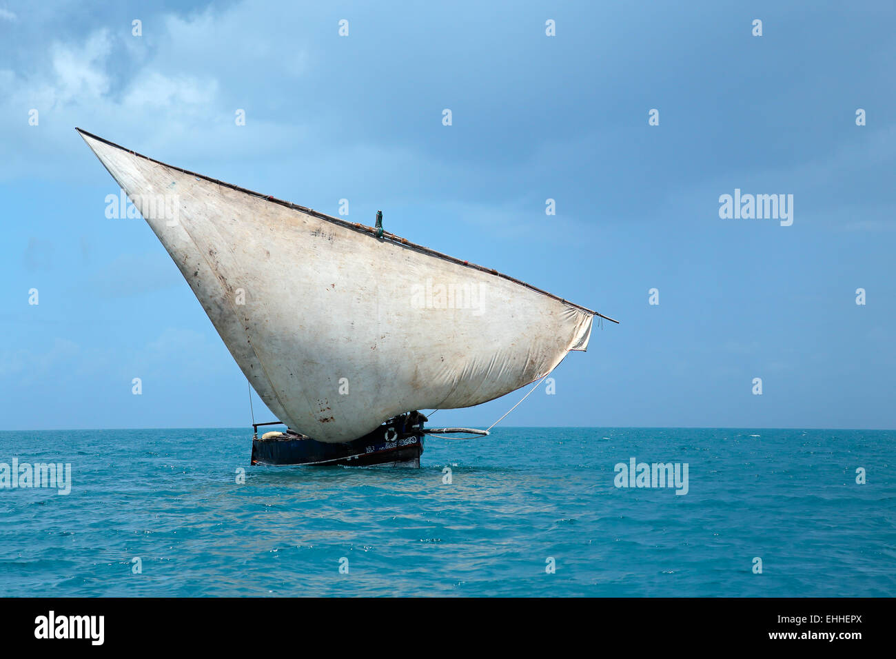Wooden sailboat (dhow) on water with clouds, Zanzibar island Stock Photo