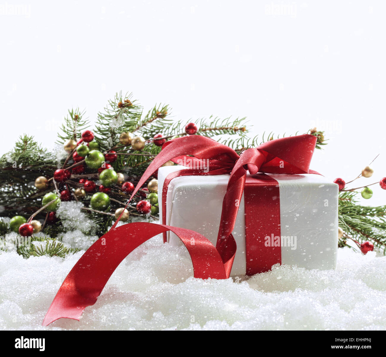 Gift box with red ribbon in snow on white Stock Photo - Alamy