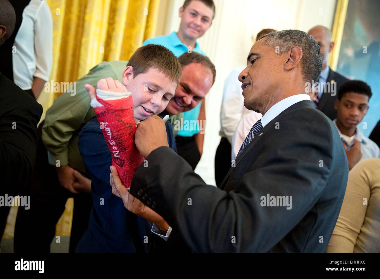 US President Barack Obama signs a boy's cast as he visits with wounded warriors and their families in the East Room during a tour of the White House September 22, 2014 in Washington, DC. Stock Photo