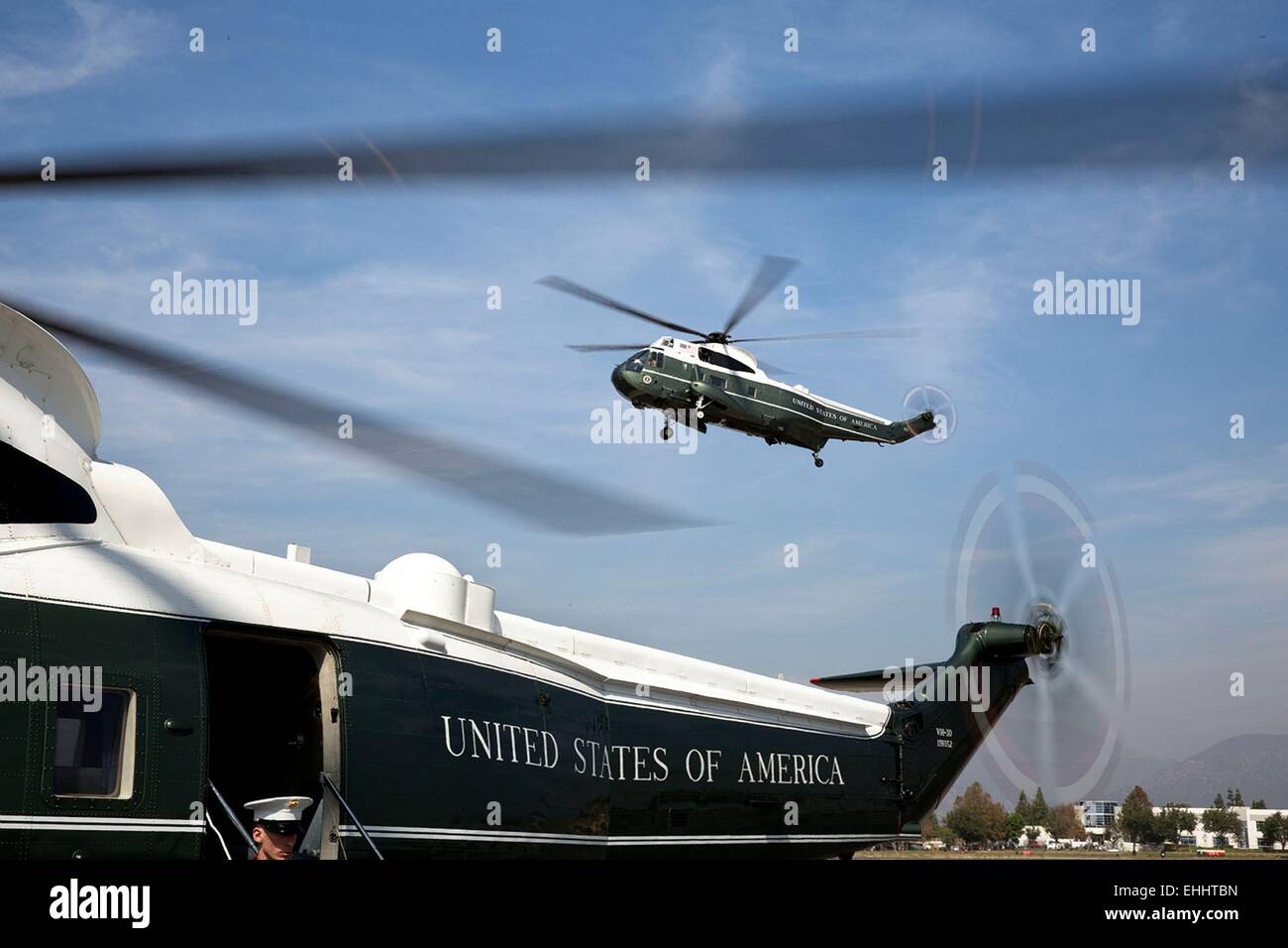 Framed by helicopter Nighthawk Two, Marine One comes in for a landing at the Brackett Field landing zone October 10, 2014 in San Dimas, California. Stock Photo