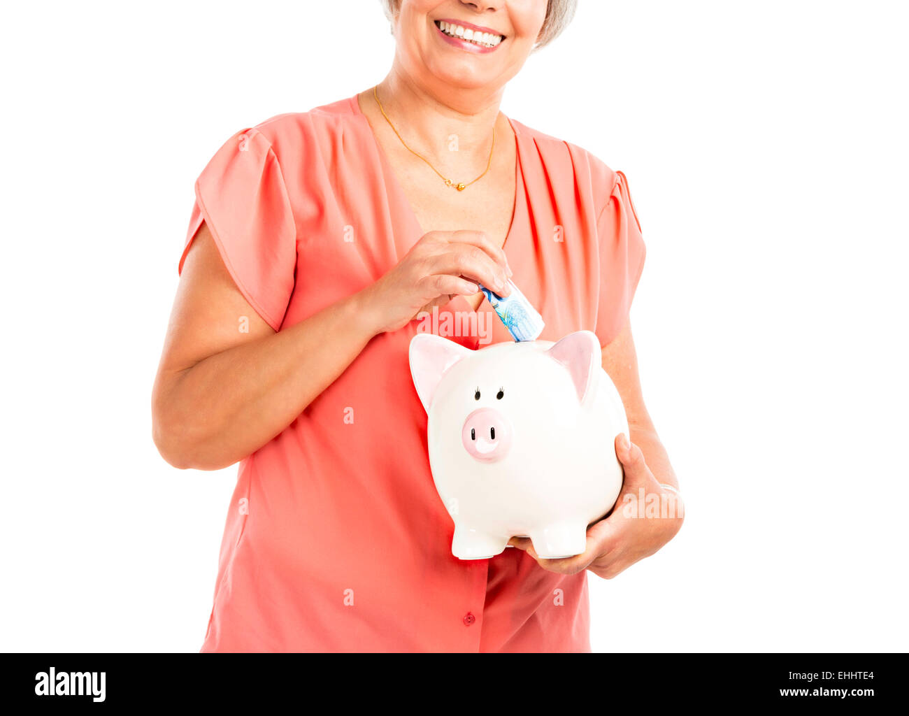 Portrait of a happy old woman putting money on a piggy bank, isolated ...