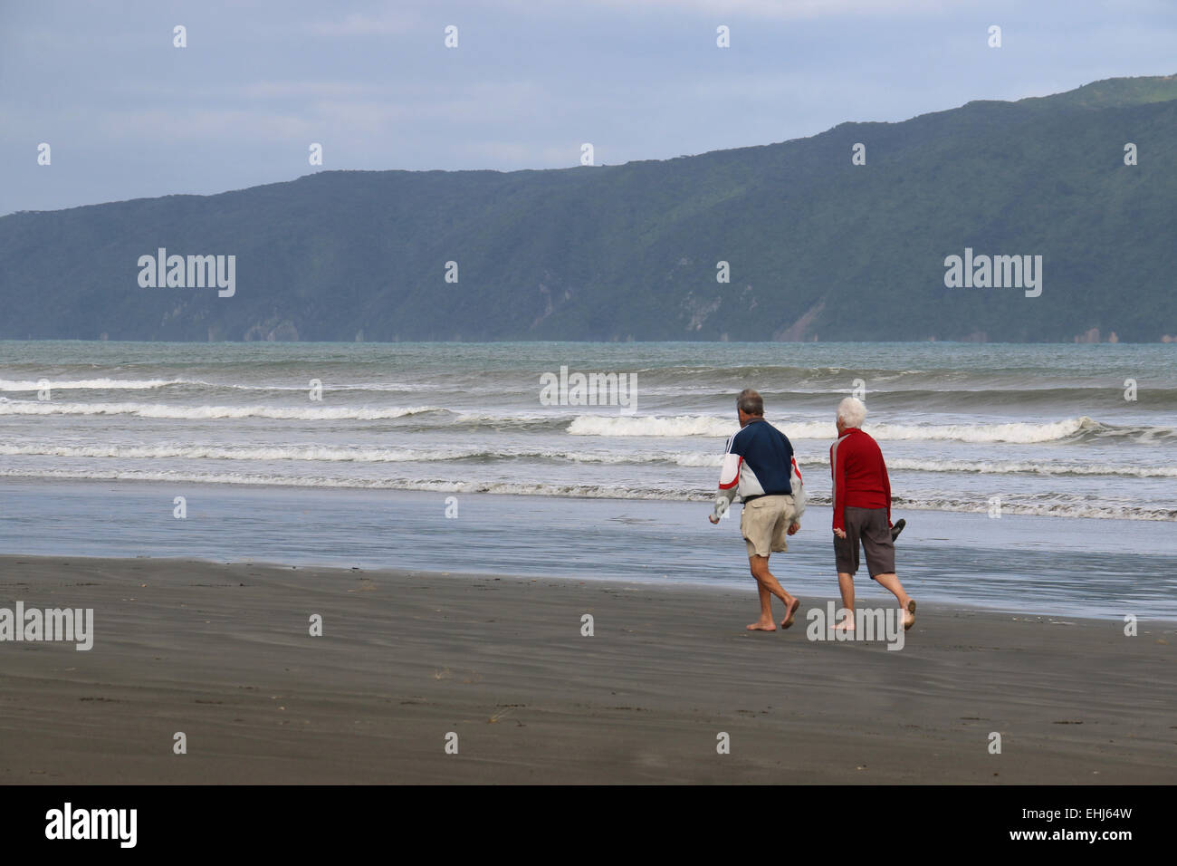 Senior citizens jogging on Waikanae Beach across from Kapiti Island in background, New Zealand Stock Photo